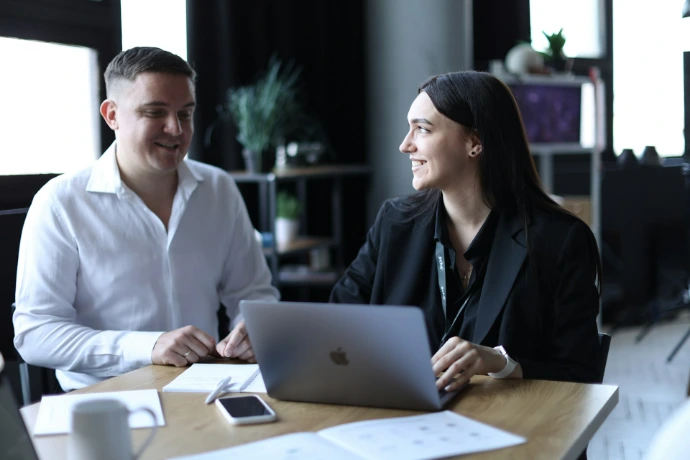 A man and a woman sitting at a table with a laptop